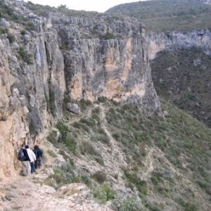Senderistas caminando por un sendero estrecho junto al cañón del embalse de Cortes