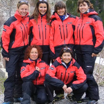 Cinco montañeras con chaquetas rojas posando en grupo antes de una expedición
