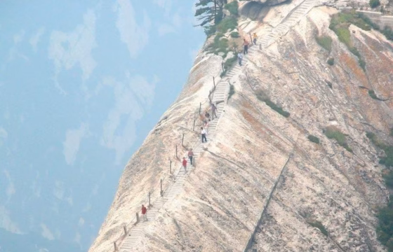 Senderistas en un paso estrecho de montaña con vistas a un barranco