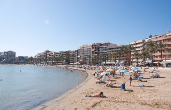 Playa con edificios en el paseo marítimo y bañistas