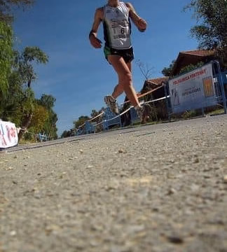 Corredor de montaña a la carrera con dorsal, fotografía en contrapicado
