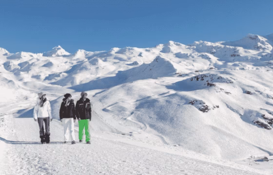 Dos personas con equipo de esquí en una pista nevada