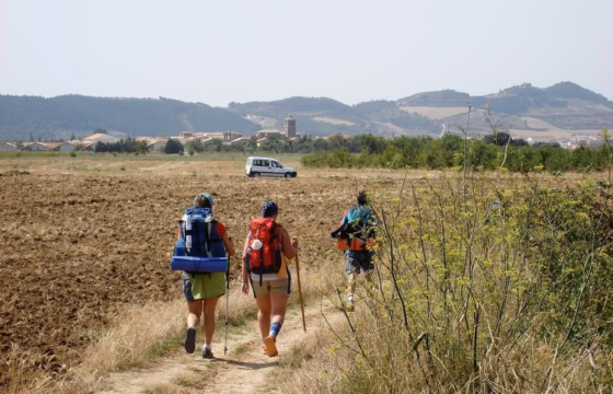 Peregrinos con mochilas caminando por un campo abierto