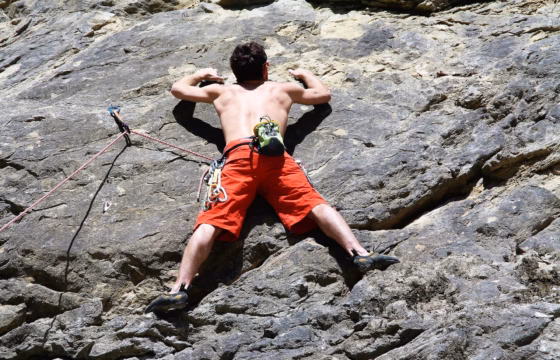 Escalador sin camiseta haciendo un ejercicio de tracción en la roca