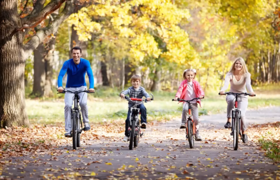 Familia en bicicleta por un camino arbolado en otoño