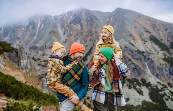 Familia con ropa de abrigo abrazándose en la montaña