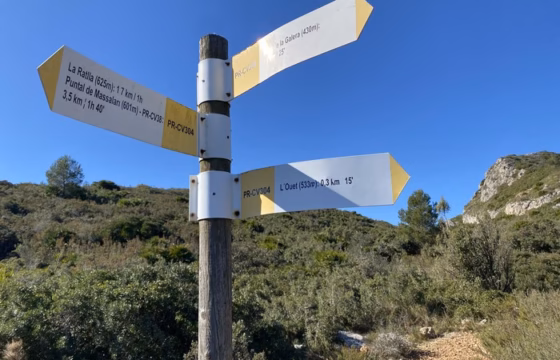 Poste de senales indicando L'Ouet a 533 metros de altitud a 0,3 km, junto con otras direcciones como La Ratlla y Puntal de Massalari