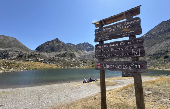 Cartel tallado del Estany de les Abelletes indicando 2.258 m de altitud, con el lago detras