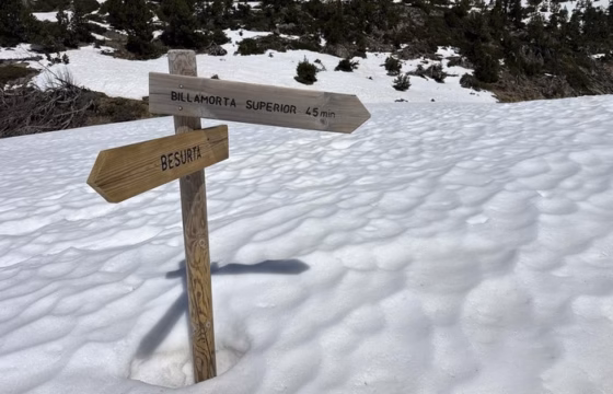 Ibon de montana completamente helado en tonos turquesa y blanco, rodeado de montanas nevadas