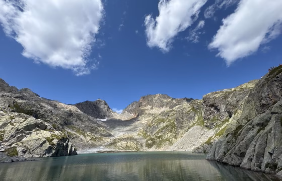 Vista panoramica del Lac Blanc con picos rocosos afilados y nubes blancas reflejadas en el agua
