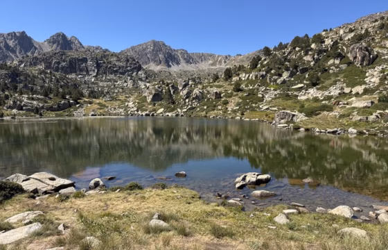Lago de montana con picos rocosos escarpados reflejados en el agua