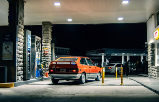 A classic red Volkswagen refuels at a rustic gas station in El Bolsón, Argentina.